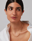 Woman wearing a gold necklace against a neutral background