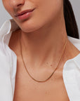 Close-up of a person wearing a gold necklace with a plain background