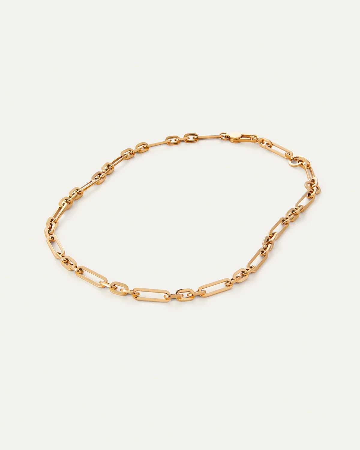 Gold chain bracelet on a light beige background