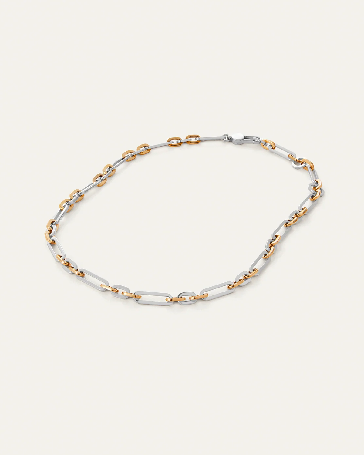 Two-tone gold and silver chain necklace on a light beige background