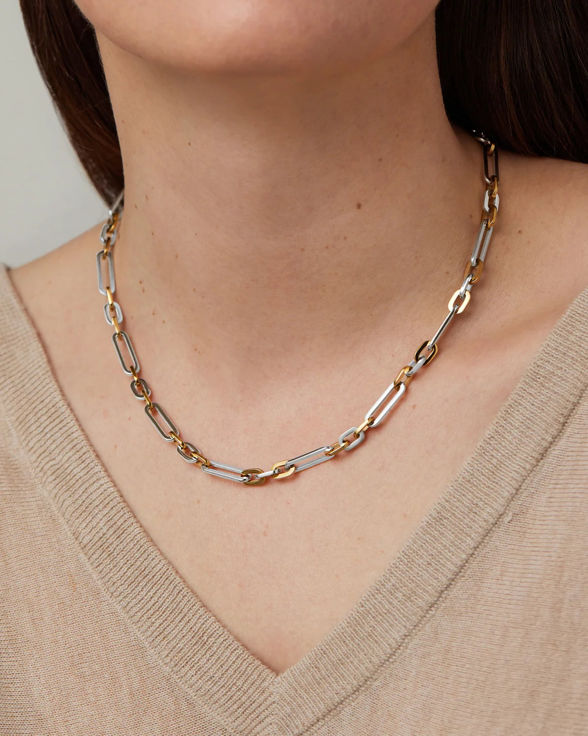 Necklace with gold and silver links worn by a person in a beige sweater.