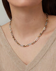 Necklace with gold and silver links worn by a person in a beige sweater.
