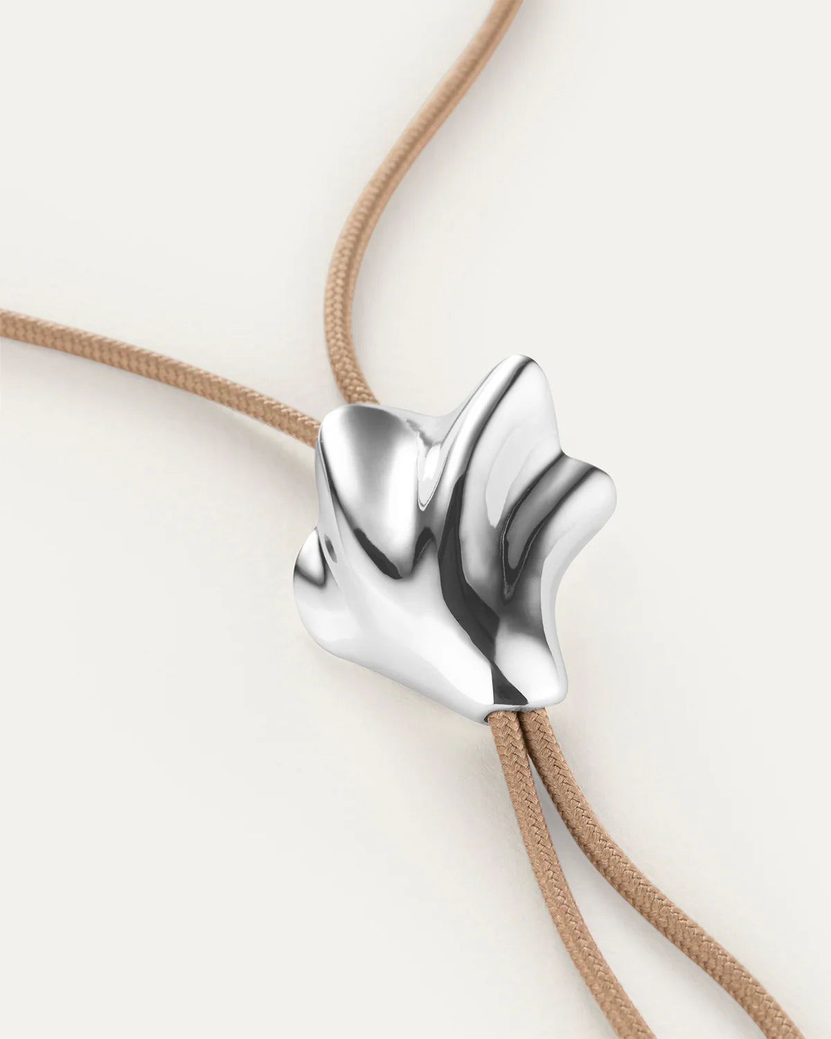 Silver pendant on a beige cord against a white background