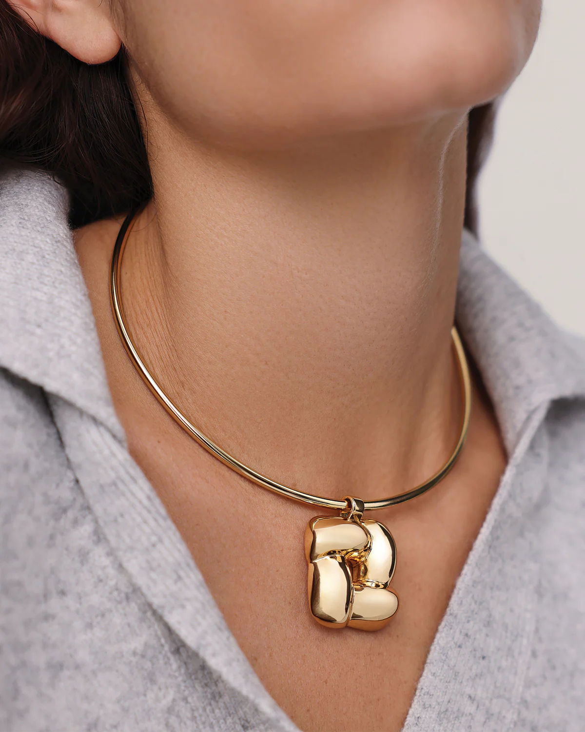Gold necklace with a letter 'B' pendant worn by a person.