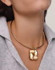 Gold necklace with a letter 'B' pendant worn by a person.