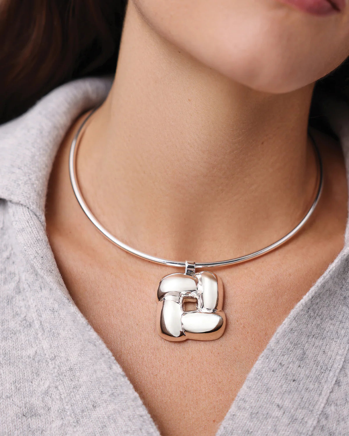 Silver necklace with a unique pendant worn by a person