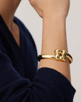 Gold bracelet on a person's wrist with a blurred background