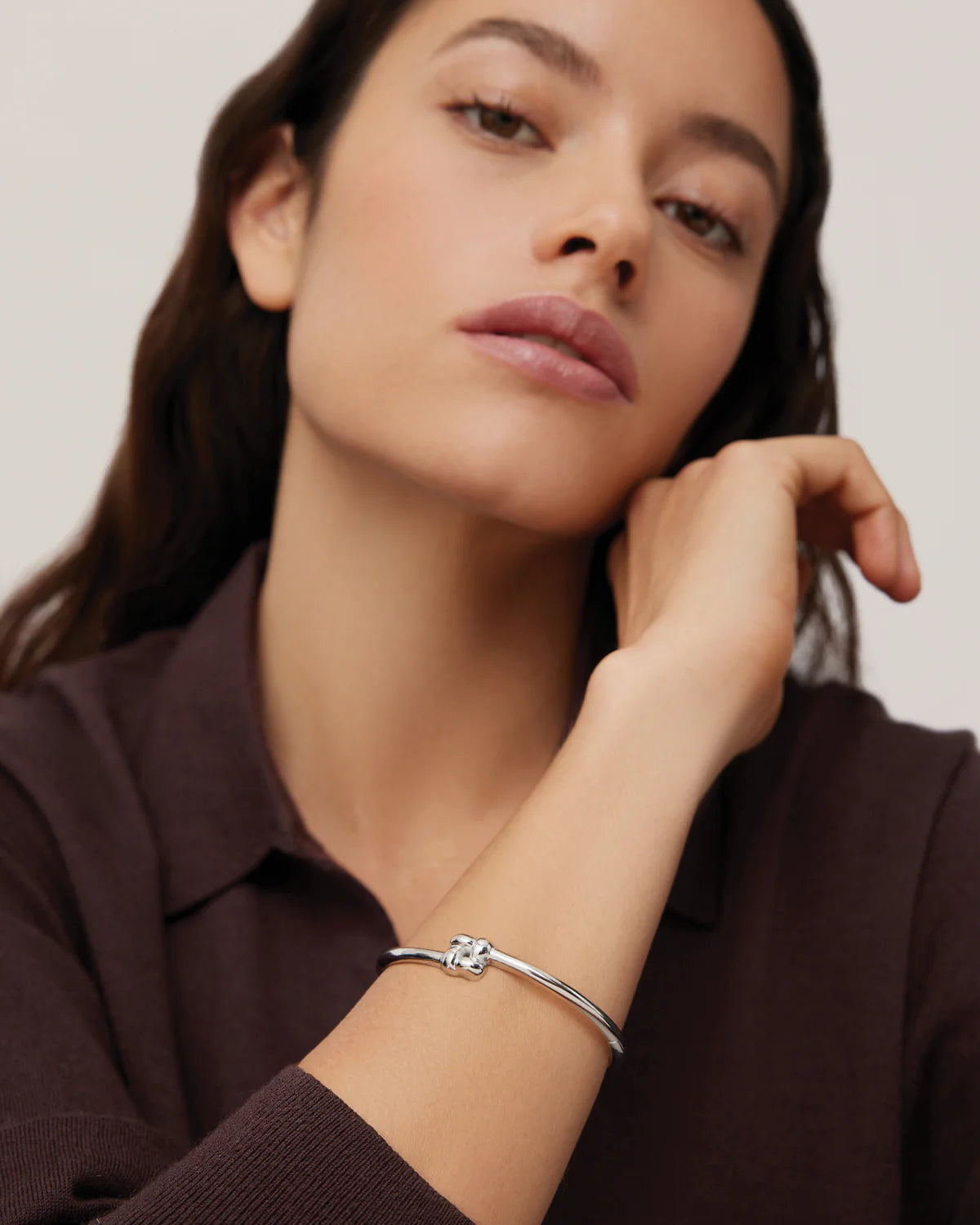 Woman wearing a silver bracelet on a neutral background