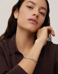 Woman wearing a silver bracelet on a neutral background