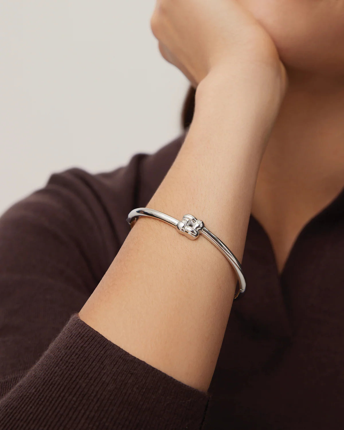 Silver bracelet on a person's wrist with a neutral background