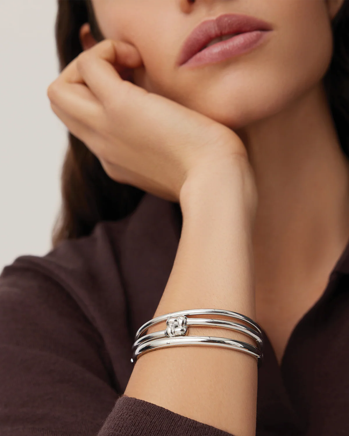 Woman wearing a silver bracelet on her wrist with a neutral background