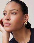 Woman wearing gold earrings with a neutral background