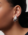 Close-up of an ear wearing a silver earring with a blurred background