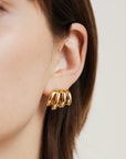 Gold hoop earring worn by a person with a neutral background