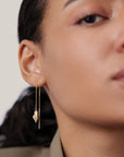 Close-up of a person wearing gold earrings with a neutral background