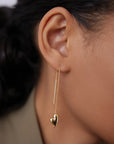 Gold heart-shaped earring worn by a person