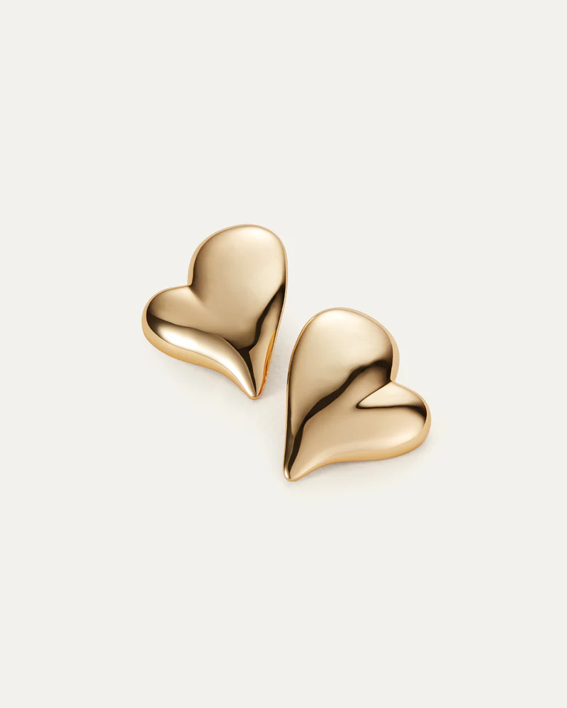 Gold heart-shaped earrings on a light beige background
