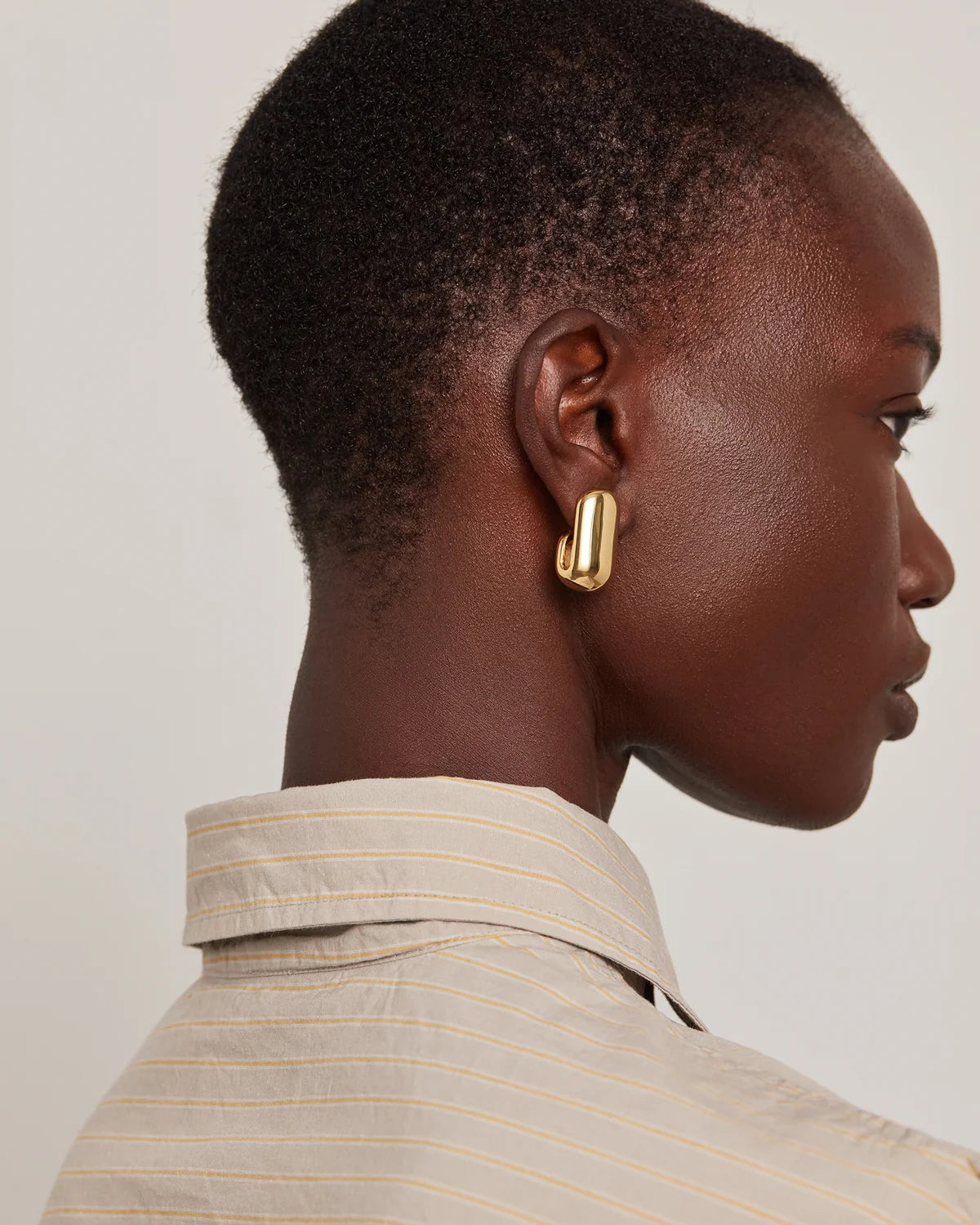 model wearing gold earrings on a white background