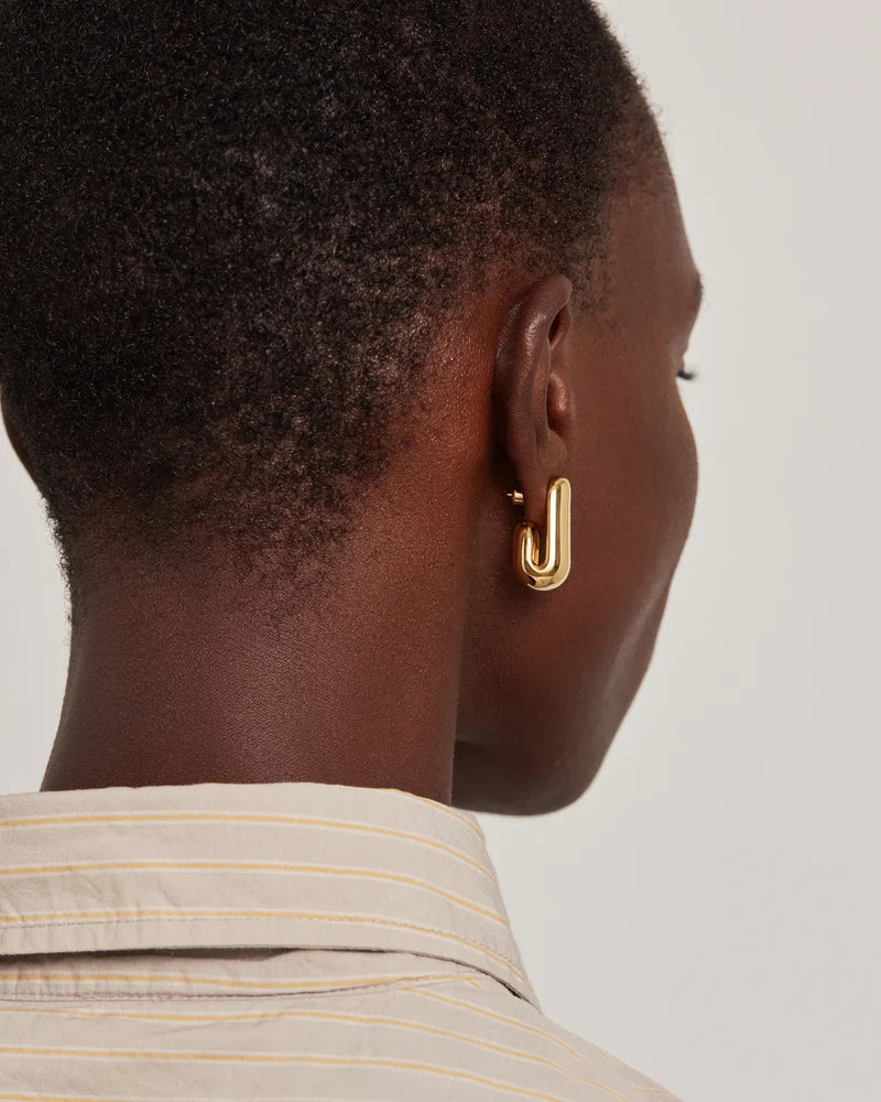 model wearing gold earrings on a white background