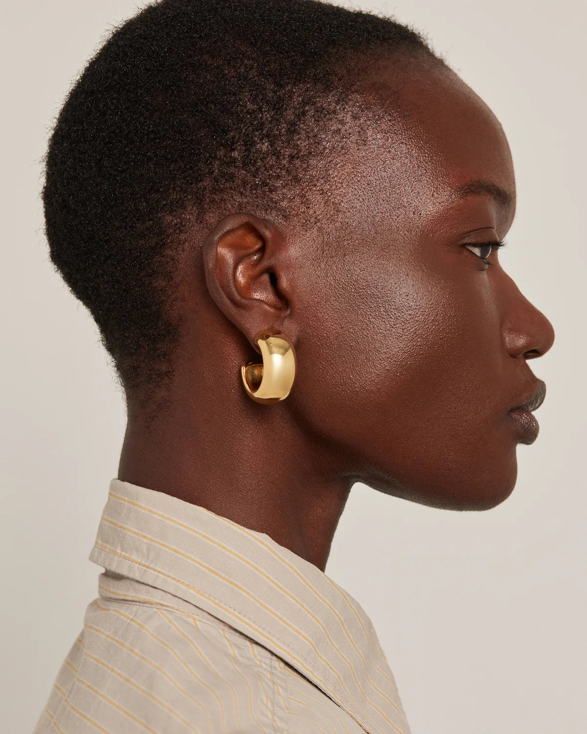 model wearing chunky gold hoops on a white background