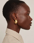 model wearing chunky gold hoops on a white background