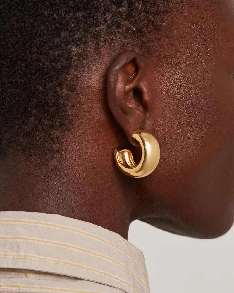model wearing chunky gold hoops on a white background