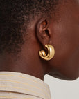 model wearing chunky gold hoops on a white background