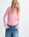 Person wearing a pink long-sleeve top and blue jeans on a white background