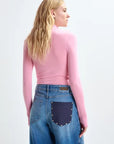 Person wearing a pink top and blue jeans with a patch on a white background