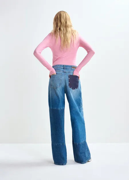 Person wearing blue jeans with a purple pocket and a pink long-sleeve shirt on a white background