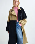 Person wearing a two-tone coat with black and beige sections on a white background