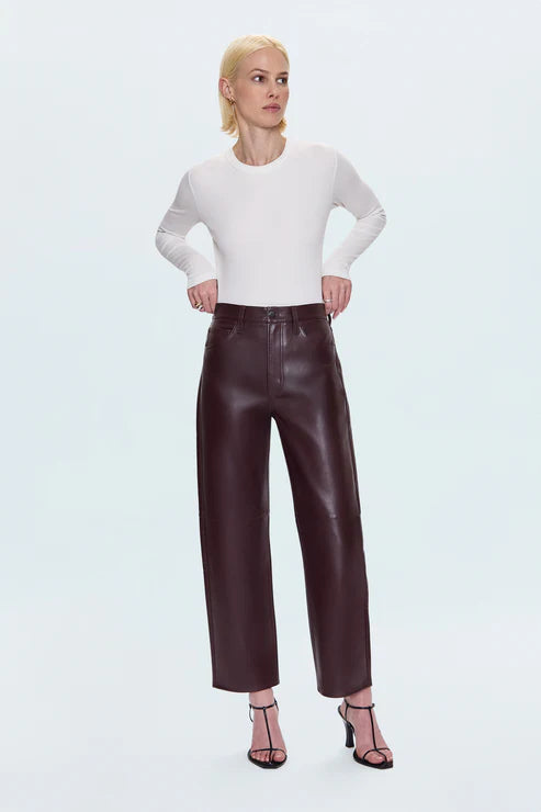 Woman wearing a white top and brown leather pants on a white background front view