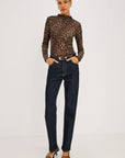model wearing a long sleeve high neck leopard top with jeans on a grey background 