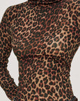close up of a model wearing a long sleeve high neck leopard top with jeans on a grey background 