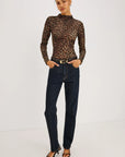 model wearing a long sleeve high neck leopard top with jeans on a grey background 