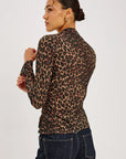 model wearing a long sleeve high neck leopard top with jeans on a grey background from the back