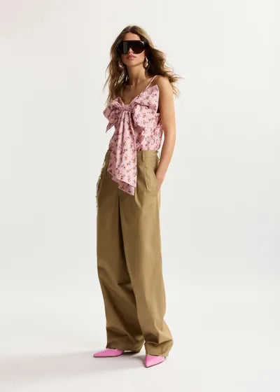 Woman wearing a pink floral top and beige pants on a white background