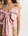 Pink floral top with a bow detail worn by a person on a white background