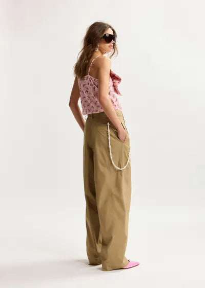 Woman wearing a floral top and beige pants on a white background
