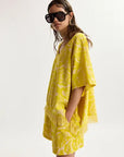Woman wearing a yellow matching set with sunglasses on a white background