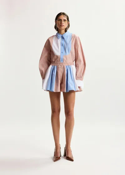Person wearing a colorful outfit with a pink, blue, and white pattern on a white background