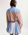 Person wearing a two-tone shirt and shorts with blue and pink stripes on a white background