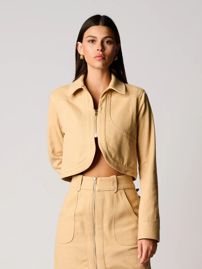 Woman wearing a beige jacket and skirt set on a plain background