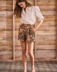 model wearing floral shorts and white button up top