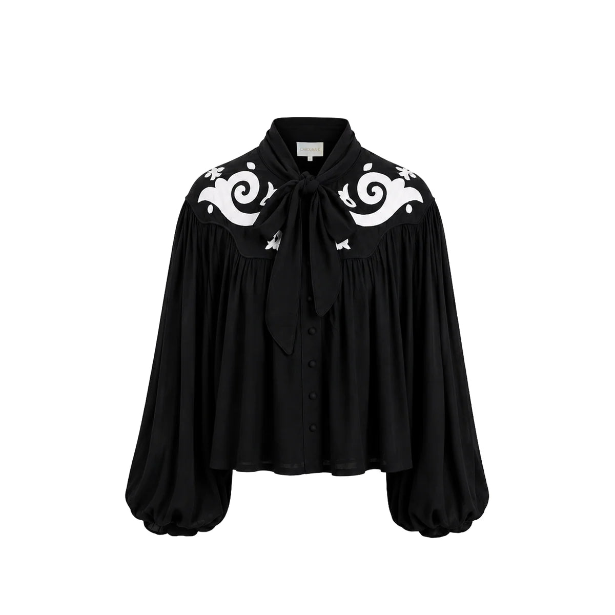 A black long-sleeve blouse with a high collar, front tie, and white baroque-style scroll embroidery on the shoulders, shown against a plain white background.