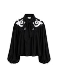 A black long-sleeve blouse with a high collar, front tie, and white baroque-style scroll embroidery on the shoulders, shown against a plain white background.