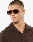 Man wearing brown sunglasses and a brown textured shirt against a white background