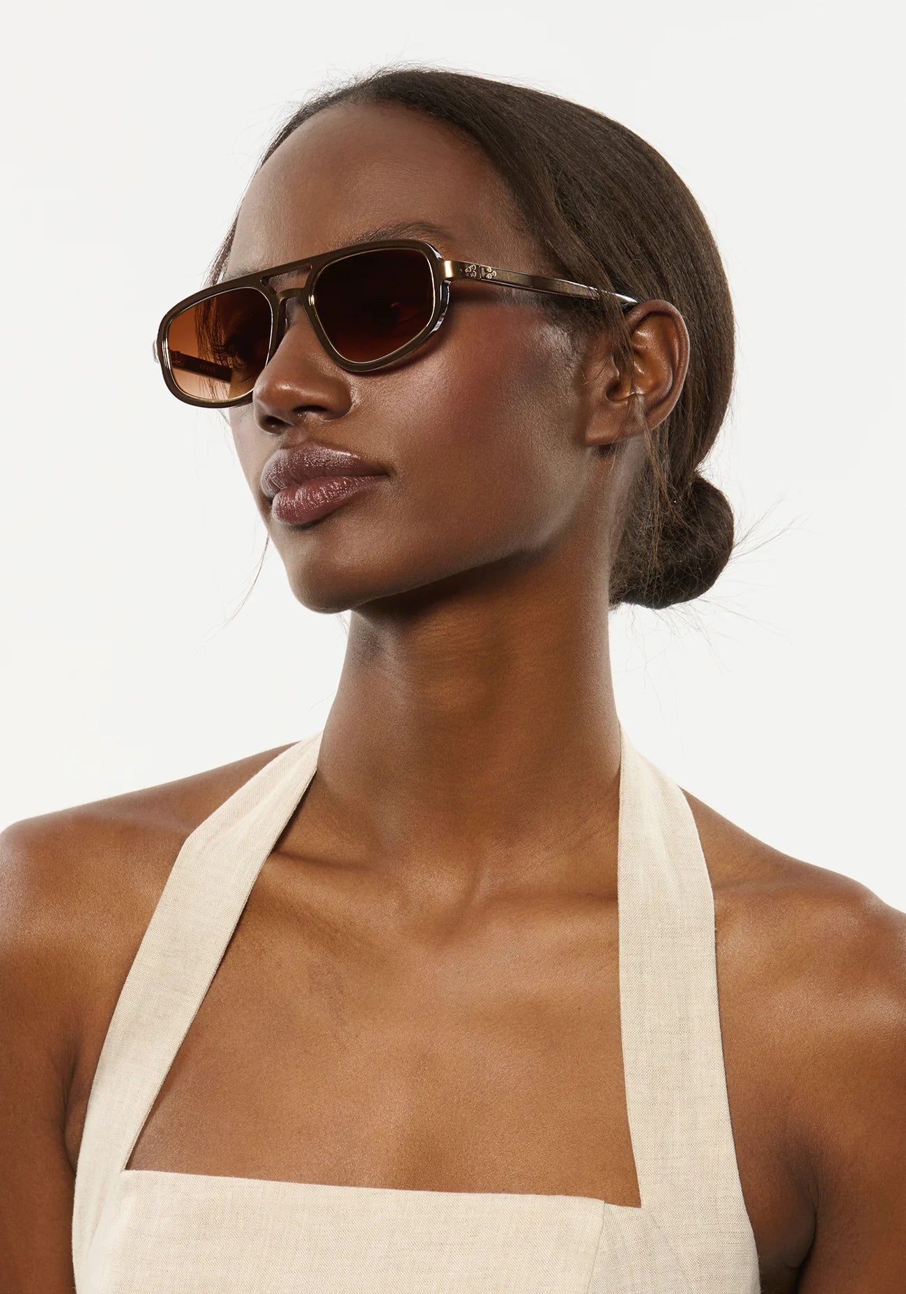 Woman wearing sunglasses and a white DRESS against a plain background