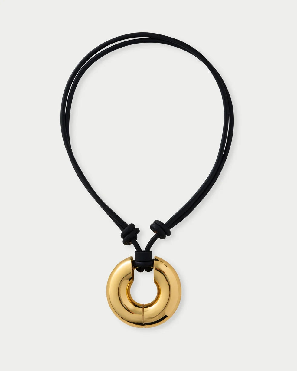 Gold pendant on a black cord against a white background