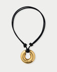 Gold pendant on a black cord against a white background